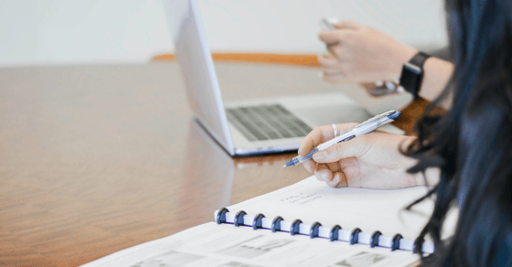 laptop with a hand of a man and notebook with a hand of a woman - everything is on the office table